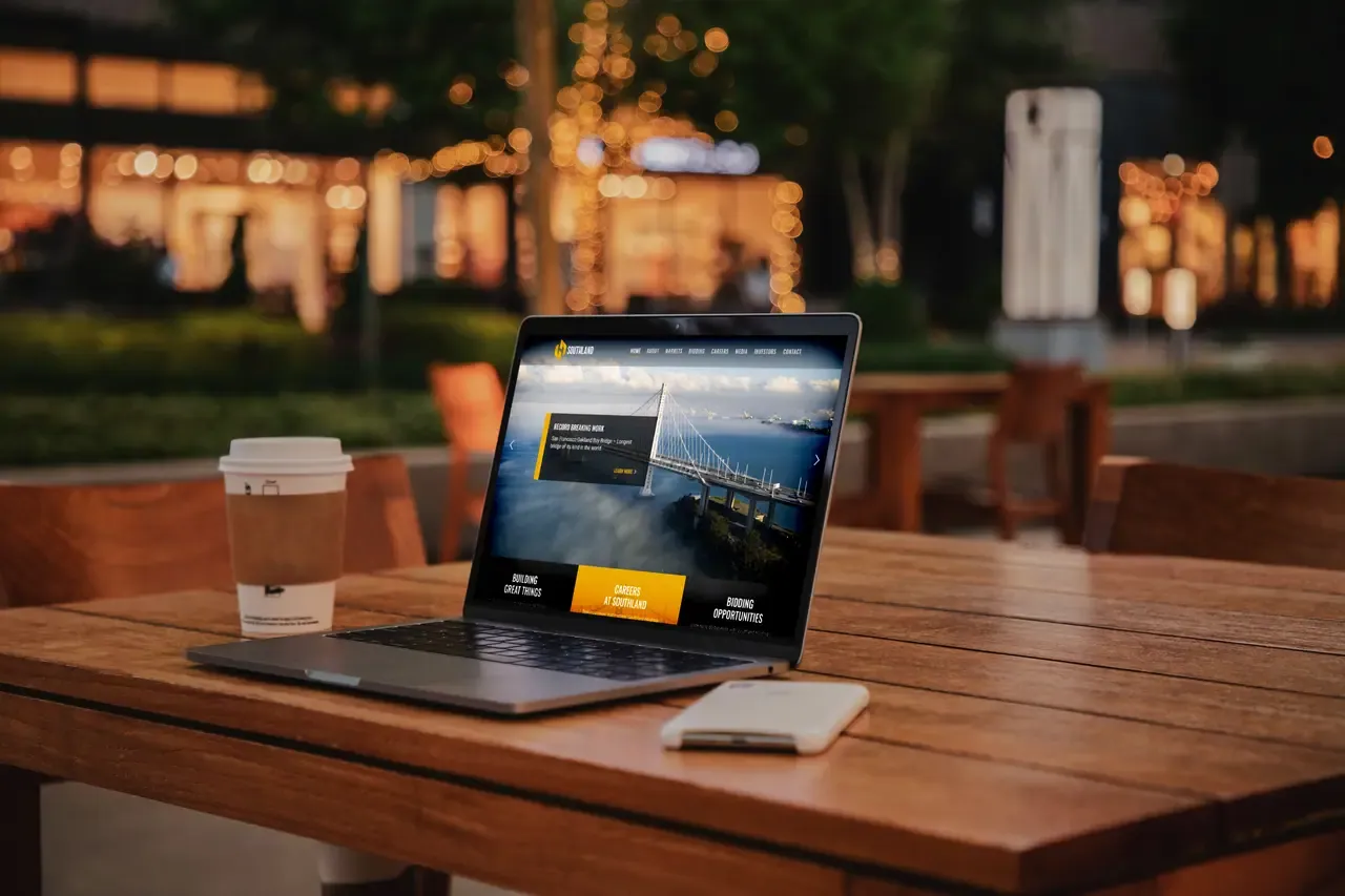 Corporate website shown on a laptop on an outdoor café table at dusk